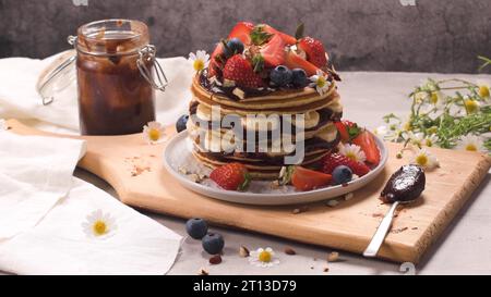 Pfannkuchen mit Banane, Heidelbeeren, Erdbeeren und Schokoladensauce auf einem Teller. Stockfoto