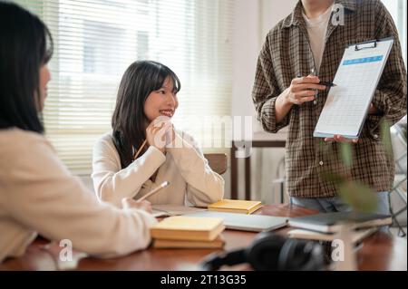 Eine schöne junge asiatische Frau konzentriert sich darauf, die Ideen ihrer Freundin zu einem neuen Projekt zu hören und ein Treffen mit ihrem Team zu führen Stockfoto