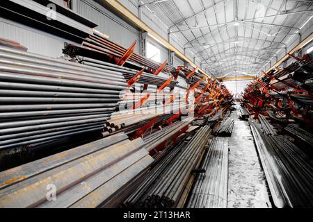 Dünne Metallstäbe stapeln sich auf einem großen Regal im Kühllager Stockfoto