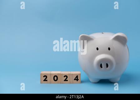 Holzwürfelrechner auf White Piggy Bank . Geschäftseinsparungen und Budgetierung von Investitionen in die Finanzplanung, Steuerkonzept für Text 2024 Stockfoto
