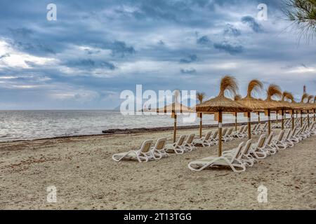 Can Picafort Beach mit Strohschirmen und Sonnenliegen, Morgen ohne Leute, bewölktes Wetter. Can Picafort, Balearen Mallorca Spa Stockfoto