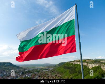 Bulgariens Nationalflagge winkt auf Pol vor sonnigem blauem Himmel Hintergrund. Stockfoto
