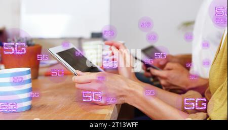 Bild von mehreren 5g-Texten über verschiedene Kollegen mit digitalen Tablets im Büro Stockfoto