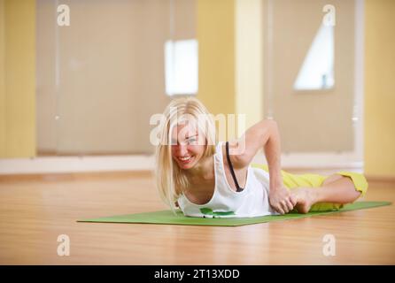 Die wunderschöne, sportlich geschnittene Yogi-Frau übt Yoga Asana Bhekasana - Froschhaltung in der Yoga-Klasse Stockfoto