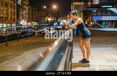 Junge blonde Läuferin, die nach dem Training den Trainingsfortschritt auf der Smart Watch-Anwendung überprüft Stockfoto