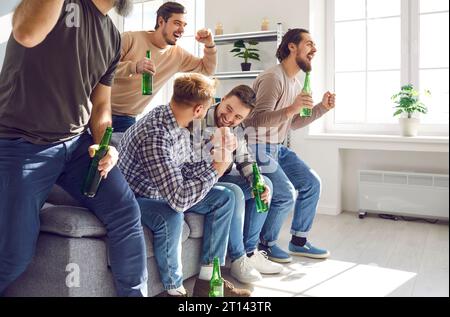 Gruppe von begeisterten Freunden, die sich zu Hause mit Bier ein Fußballspiel im fernsehen ansehen. Stockfoto