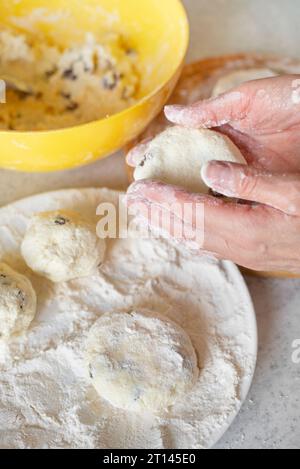 Kaukasische Frauenhände machen Hüttenkäse-Pfannkuchen mit Rosinen-Kochhintergrund Stockfoto