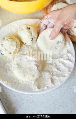 Kaukasische Frauenhände machen Hüttenkäse-Pfannkuchen mit Rosinen-Kochhintergrund Stockfoto