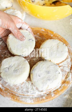 Kaukasische Frauenhände machen Hüttenkäse-Pfannkuchen mit Rosinen-Kochhintergrund Stockfoto