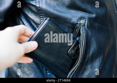 Die Hand zieht Papiergeld und Karte aus der Tasche. Ein Dieb hat einen Mann ausgeraubt. Bargelddiebstahl, kriminelles Konzept. Stockfoto