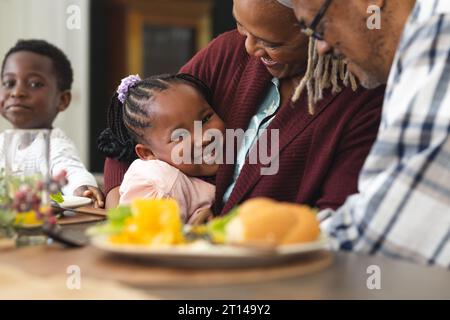afroamerikanische Enkelin und Großmutter, die sich beim Thanksgiving-Dinner umarmen Stockfoto