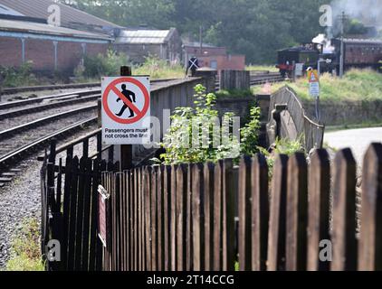 Beachten Sie, dass die Passagiere die Strecke nicht an der Keighley Station auf der Keighley & Worth Valley Railway überqueren dürfen, wenn sich ein Dampfzug nähert. Stockfoto