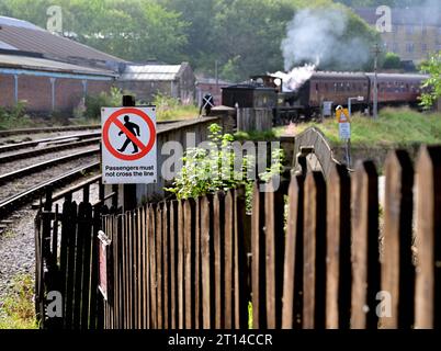 Beachten Sie, dass die Passagiere die Strecke nicht an der Keighley Station auf der Keighley & Worth Valley Railway überqueren dürfen, wenn sich ein Dampfzug nähert. Stockfoto