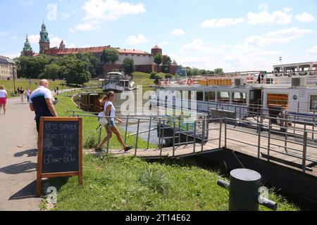 Krakau. Krakau. Polen. Vergnügungsboote fahren auf dem Weichsel-Hafen und Boarding-Platz vor der königlichen Burg Wawel, die im Hinterland zu sehen ist Stockfoto