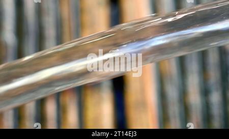 Der Wasserstrahl fließt aus einem blauen Swimmingpool auf eine Holzterrasse. Stockfoto