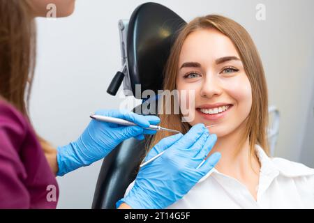 Porträt einer jungen lächelnden Frau, die vor der Zahnbehandlung in der stomatologischen Praxis auf dem Stuhl sitzt Stockfoto