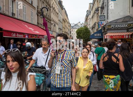 Ein Reiseleiter hält einen Schirm hoch, während er eine Gruppe von Touristen durch das überfüllte Quartier Latin in Paris, Frankreich, führt. Stockfoto