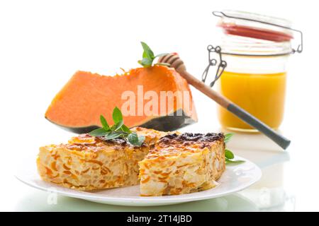 Gekochter Hüttenkäseauflauf mit Kürbisstücken innen, isoliert auf weißem Hintergrund. Stockfoto