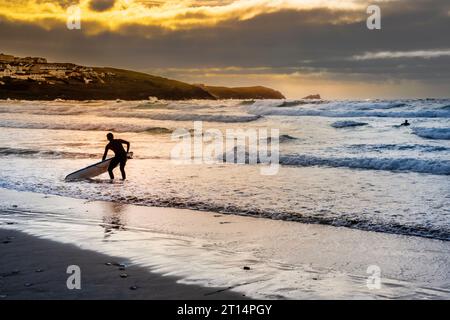Die Silhouette eines Surfers, der bei Abendlicht am Fistral Beach in Newquay in Cornwall in Großbritannien steht. Stockfoto