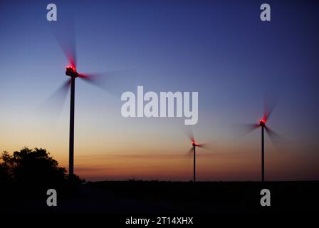 Windkrafterzeugung, Windturbinen auf Ackerland bei Nacht. Stockfoto