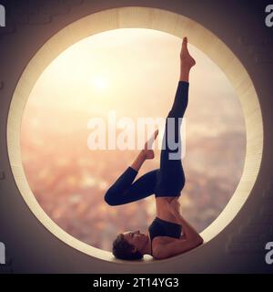 Schöne sportlich geschnittene Yogi-Frau übt Yoga Handstand Asana Salamba Sarvangasana - Schulterstand in einem runden Fenster mit arial Blick auf die Stadt Stockfoto