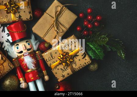 Hintergrund des Weihnachtskonzepts. Blick von oben auf Weihnachtsschmuck und weihnachts-Holznussknacker-Spielzeugsolider über einem dunklen Hintergrund Stockfoto