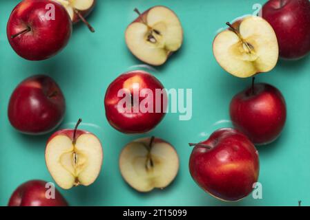 Ganze und halbe rote Äpfel schweben auf hellblauem Hintergrund Stockfoto