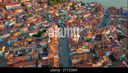 Blick aus der Vogelperspektive auf Burano farbenfrohe Häuser, entlang des Fondamenta Dammes, mit Fischerbooten und Brücken, Venedig, Italien bei Sonnenaufgang goldene Stunde Stockfoto