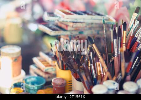 Pinsel und Aquarellfarben auf dem Tisch in einer Werkstatt, selektiver Fokus, Nahaufnahme Stockfoto