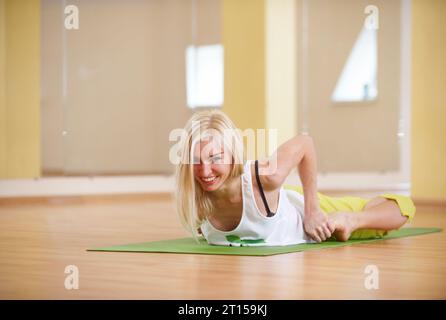 Die wunderschöne, sportlich geschnittene Yogi-Frau übt Yoga Asana Bhekasana - Froschhaltung in der Yoga-Klasse Stockfoto