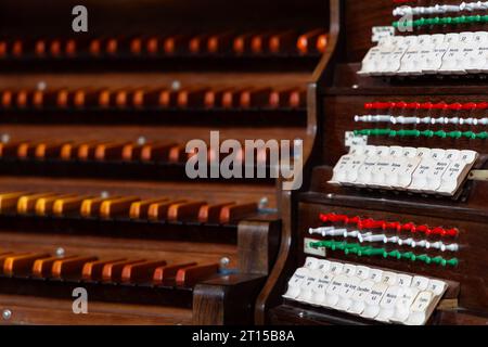 Holztastatur einer antiken Kirchenpfeifenorgel. Das Foto wurde in der Halbdunkel des Kircheninnenraums aufgenommen Stockfoto