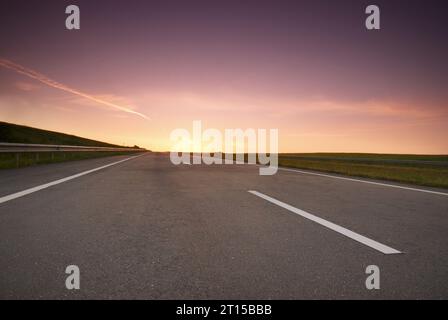 Leere Autobahn mit aufgehender Sonne am Horizont Stockfoto