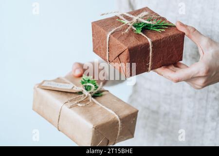 Weibliche Hände halten handgefertigte Geschenkboxen, die sorgfältig in umweltfreundliche Verpackungen verpackt sind. Nachhaltiges und umweltbewusstes Wohnkonzept Stockfoto