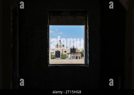 Schwarze Wassertanks auf den Dächern, von Afar aus gesehen durch ein Fenster in einer kleinen Stadt in Palästina Stockfoto