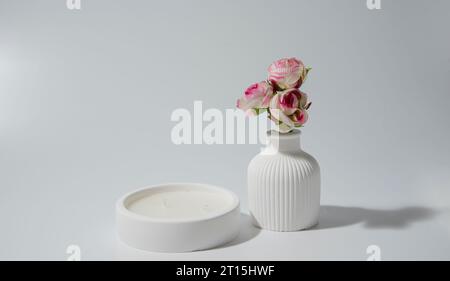 Kerze in weißem Keramiktopf auf weißem Hintergrund, eine Vase mit einer Kerze. Gemütliches Haus natürliches Öko-Dekor Stockfoto