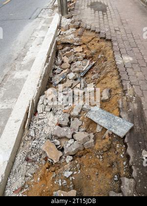 Der Fußweg ist von der Erosion des Regens in der Nähe der Asphaltstraße in der Stadt unterbrochen, Vorderansicht für den Kopierraum. Stockfoto