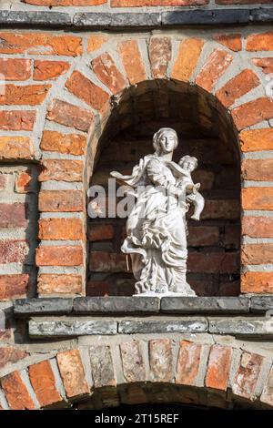 Statue der Jungfrau Maria mit dem Jesuskind in der Nische über der Eingangstür an der Beguinage von Aarschot aus dem 17. Jahrhundert im flämischen Brabant in Flandern, Belgien Stockfoto