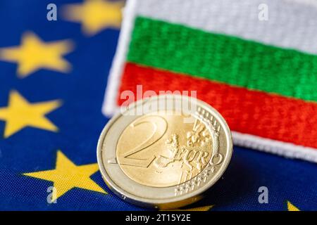 Einführung des Euro durch Bulgarien, Beitritt zur Eurozone, Wirtschaftskonzept, Euro-Münzen, bulgarisches Geld, Flagge Bulgariens und der Europäischen Union Stockfoto