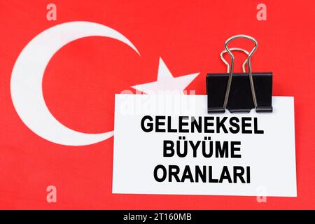 Wirtschafts- und Finanzkonzept. Auf der Flagge der Türkei liegt eine Visitenkarte mit der Aufschrift "traditionelle Wachstumsraten". Text auf Türkisch. Stockfoto