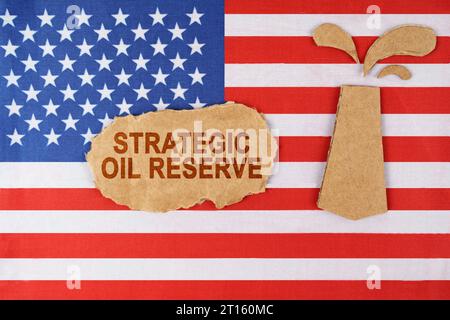 Auf der US-Flagge befindet sich eine aus Pappe geschnittene Ölplattform und ein Schild mit der Aufschrift Strategic Oil Reserve. Stockfoto