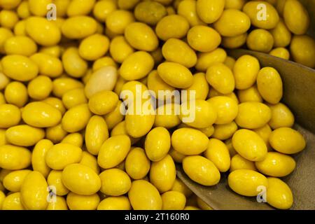 Auf der Theke stehen Süßigkeiten - Erdnüsse in gelber Glasur und ein Löffel. Süßwarenladen. Stockfoto