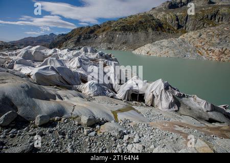 Klima | Albedo | Rhone: Riesige Vliesdecken decken decken Teile des Rhone-Gletschers in der Schweiz ab, um das unvermeidliche Schmelzen von Schnee und Eis zu verhindern. 2018 schmolz der Rhone-Gletscher (im Bild) mehr als 70 Zentimeter dick. Laut einem aktuellen Bericht der Schweizerischen Akademie der Wissenschaften verlor derselbe Gletscher in den beiden Jahren 2022/2023 über 2 Meter an Dicke. Während Schnee ein brillanter Reflektor der Sonnenenergie ist, absorbiert das dunklere Eis die Energie stattdessen und beschleunigt das Schmelzen des Gletschers. Die Farbe und Dunkelheit des Gletschereises variiert überall Stockfoto