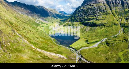 Luftpanorama des westlichen Teils von Glen Coe mit dem Süßwasserloch Loch Achtriochtan und dem Fluss Coe, daneben die A82 Stockfoto