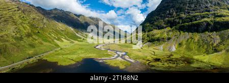 Luftpanorama des westlichen Teils von Glen Coe mit dem Süßwasserloch Loch Achtriochtan und dem Fluss Coe, daneben die A82 Stockfoto