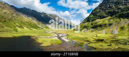 Luftpanorama des westlichen Teils von Glen Coe mit dem Süßwasserloch Loch Achtriochtan und dem Fluss Coe, daneben die A82 Stockfoto