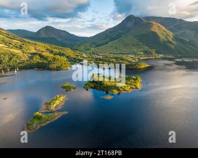 Aus der Vogelperspektive auf die Insel Eilean Munde, dahinter das Dorf Ballachulish mit dem Hafen und dem ehemaligen Schieferbruch im westlichen Teil von Stockfoto