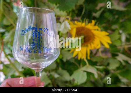 Weinglas mit dem Logo des Chatillon EN Diois Arts and Wine Festival ('Fête des Arts et de la vigne'), mit Sonnenblume im Hintergrund Stockfoto