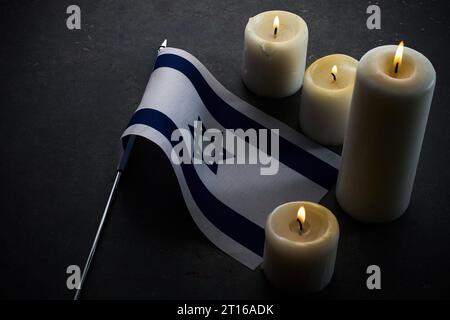 Brennende Kerzen und Flagge Israels auf dunklem Hintergrund. Holocaust-Gedenktag Stockfoto