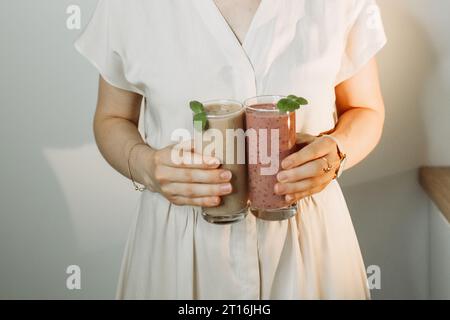 Eine Frau hält einen Smoothie mit grünem Spinat, Pistazien und einem Heidelbeercocktail in der Hand. Wohlbefinden und Gewichtsreduktion. Stockfoto