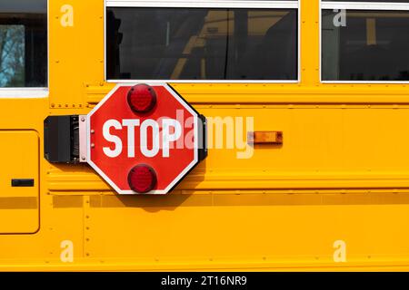 Ein großes rotes Stoppschild neben einem gelben Schulbus. Stockfoto